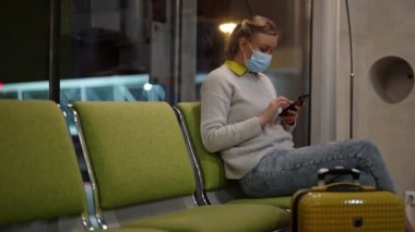 Tıbbi maskeli kadın havaalanında kayıt yaptırmak için bekliyor..