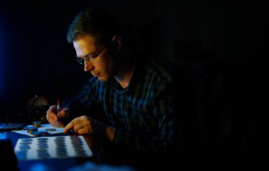 Erkek numismatist madeni para koleksiyonunu inceliyor.