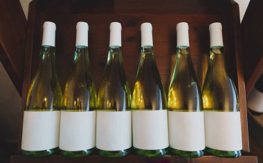 beyaz şarap şişeleri ahşap raf üzerinde yığılmış.