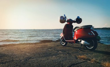 Deniz kıyısında kırmızı renkli scooter..