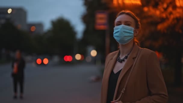医療マスクの女性はバス停でバスを待っています — ストック動画