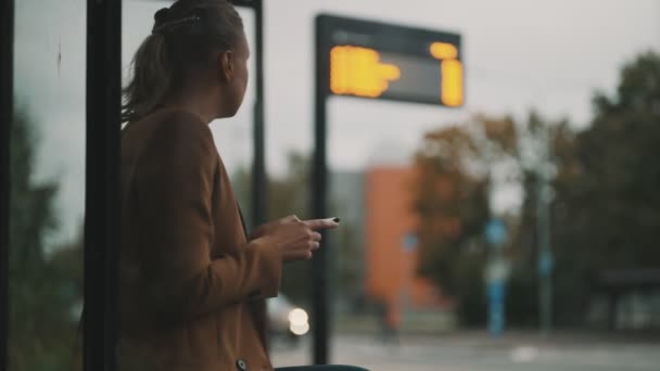 Mulher Com Smartphone Está Esperando Por Ônibus Parada Ônibus — Vídeo de Stock