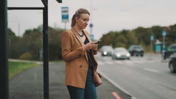 Kvinna Med Smartphone Väntar Bussen Vid Busshållplatsen — Stockvideo