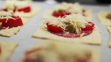 Salamlı, peynirli, zeytinli ve domatesli mini pizza pişirmek.