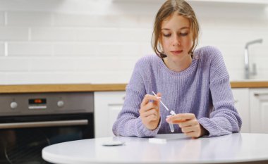 Okullu kız evde COVID-19 antijen testi yapıyor..