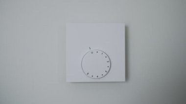 Kadın ısınmak için ısıtma termostatını açıyor..