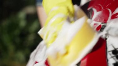 Eldivenli bir kadın arabanın farlarını süngerle yıkıyor..