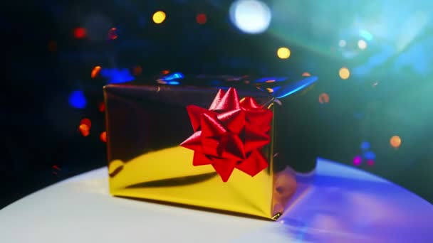Újévi ajándék fényes csomagolásban a karácsonyfa mellett.