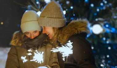 Anne ve kızı Noel ağacının yanında Bengal ateşiyle.