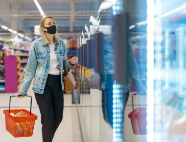 Markette tıbbi maskeli bir kadın..