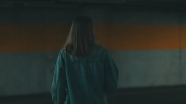 Yeraltı otoparkında arabasının kilidini açan kadın..