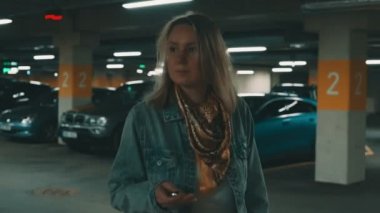 Yeraltı otoparkında arabasının kilidini açan kadın..