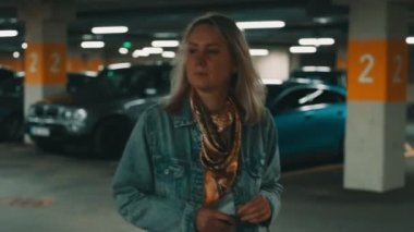 Yeraltı otoparkında arabasının kilidini açan kadın..