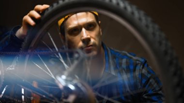 Technician examines wheel of the bicycle. Bicycle repair workshop.