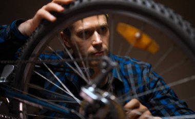 Technician examines wheel of the bicycle. Bicycle repair workshop.