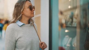 Kadın turist hediyelik eşyalarla dükkanın camına bakıyor..