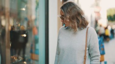 Kadın turist hediyelik eşyalarla dükkanın camına bakıyor..
