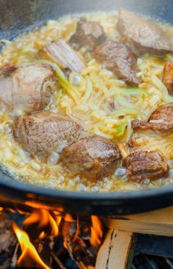 Et kazanda ateşte pişiyor. Pilaf 'ın aşçılığı adım adım.