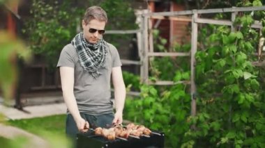 Güneş gözlüklü yakışıklı adam shashlik yapıyor..