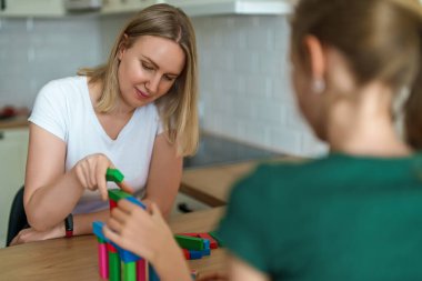 Kadın ve kız evde jenga kulesi oyunu oynuyorlar..
