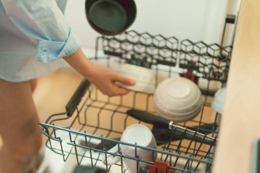 Kadın bulaşık makinesinden bulaşıkları boşaltıyor..