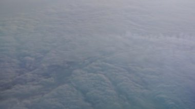 Uçak penceresinden bulutların görüntüsü.