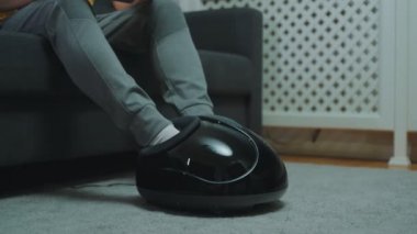 Adam bacaklarına elektrikli ayak masajı yapıyor..
