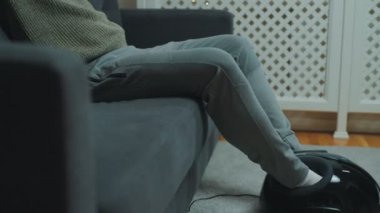 Adam bacaklarına elektrikli ayak masajı yapıyor..