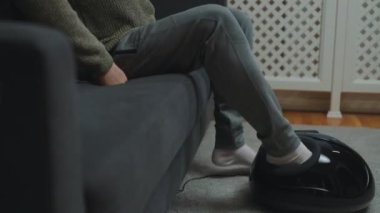 Adam bacaklarına elektrikli ayak masajı yapıyor..