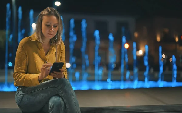 Donna Con Smartphone Seduta Vicino Alla Fontana Sera Estate — Foto Stock