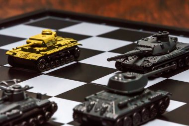 Satranç tahtasındaki oyuncak tanklar. Askeri strateji kavramı.