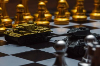 Satranç tahtasında satranç oynayan oyuncak tanklar. Askeri strateji kavramı.