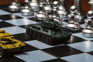 Satranç tahtasında satranç oynayan oyuncak tanklar. Askeri strateji kavramı.