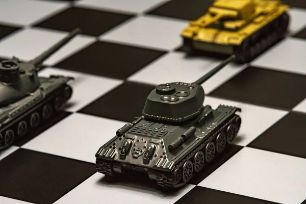 Satranç tahtasındaki oyuncak tanklar. Askeri strateji kavramı.