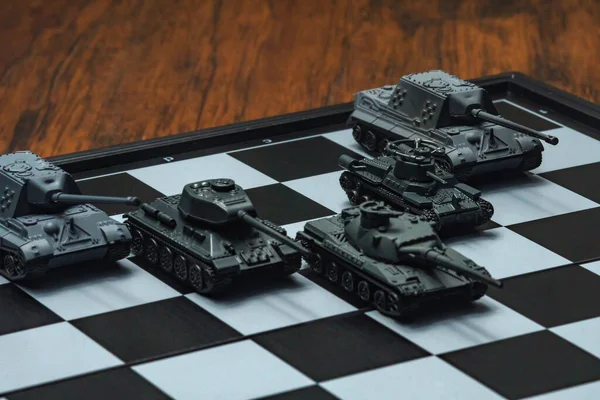 Satranç tahtasındaki oyuncak tanklar. Askeri strateji kavramı.