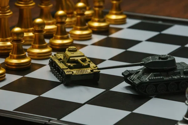 Satranç tahtasında satranç oynayan oyuncak tanklar. Askeri strateji kavramı.
