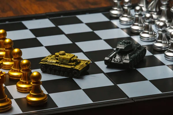 Satranç tahtasında satranç oynayan oyuncak tanklar. Askeri strateji kavramı.
