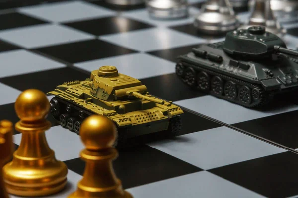 Satranç tahtasında satranç oynayan oyuncak tanklar. Askeri strateji kavramı.