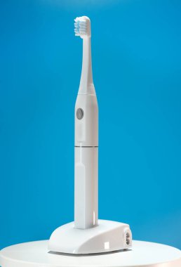 Mavi arka planda elektrikli ultrasonik diş fırçası.