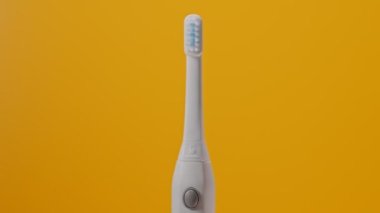 Sarı arka planda elektrikli ultrasonik diş fırçası..