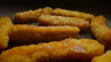 Chicken nuggets frying in a pan.