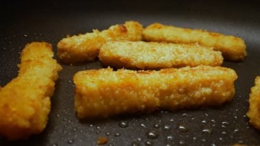 Chicken nuggets frying in a pan.