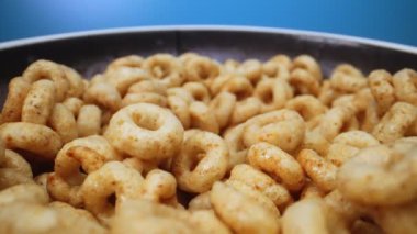 Mavi zemin üzerinde mısır gevreği çemberleri olan döner kase.