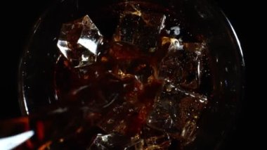 Pouring of cola with ice cubes.