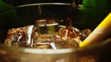 Pouring of cola with ice cubes.