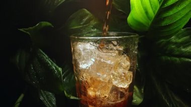Pouring of cola with ice cubes.
