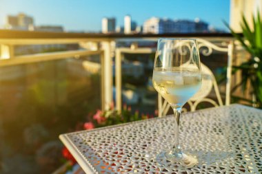 Glass of white wine on the balcony at sunset.