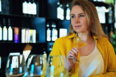 Kadın şaraphanede beyaz şarap tadıyor..