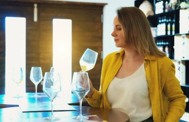 Kadın şaraphanede beyaz şarap tadıyor..