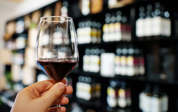 Man Hand Holds Glass Red Wine Background Bottles — Stockfoto